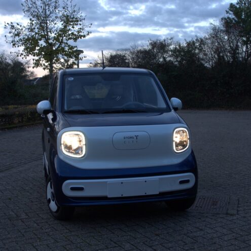 etors city wit blauwe brommobiel voorkant met de lampen aan die buiten staat puramobi